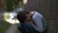 Pained sad lonely boy sits on the ground on nature in deep depression, no one is waiting for the boy at home Royalty Free Stock Photo