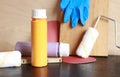 Paint bottles, paint roller, blue gloves and sandpaper. Items needed for repairs on a wooden table Royalty Free Stock Photo