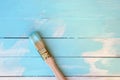 Paint brush in blue paint on a background of wooden painted boards. Royalty Free Stock Photo