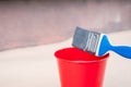 Paint brush and a bucket with paint next to a building exterior wall. Painting house plinth outside. Home renovation. Nobody Royalty Free Stock Photo