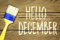 paint brush and painting hello december on wooden background.