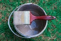 Paint brush placed on the paint bucket in the green grass area Royalty Free Stock Photo