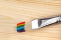 Paint brush with rainbow strokes on bristle on wooden background Royalty Free Stock Photo