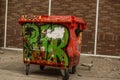 Paint brushed trash bin with graffiti against stone brick wall Royalty Free Stock Photo