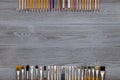 Paint brushes, color pencils on grey wooden background, art table. Top view with copy space