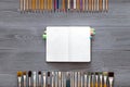 Paint brushes, color pencils and notebook on grey wooden background, art table. Top view with copy space Royalty Free Stock Photo