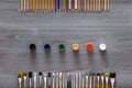 Paint brushes, color pencils and watercolors on grey wooden background, art table. Top view with copy space