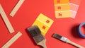 Paint Brushes, Color Samples, Tape and Paint Sticks on a Red Surface