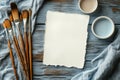 Paint brushes, paper, and a cup are arranged on a table, ready for creative work. Royalty Free Stock Photo