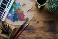 Paint brushes, watercolors and palette on wooden table.