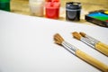 Paint brushes and a white sheet of paper. Composition of watercolor and gouache paints on a wooden background. Royalty Free Stock Photo