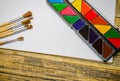 Paint brushes and a white sheet of paper. Composition of watercolor and gouache paints on a wooden background. Royalty Free Stock Photo