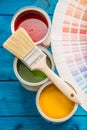 Paint cans color palette, cans opened with brushes on blue table Royalty Free Stock Photo