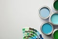 Paint cans and color palette on white background, top view.