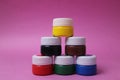 Paint in jars with white lids stands in a row, tower on a pink background: acrylic, watercolor, oil, red, yellow, blue, black, Royalty Free Stock Photo