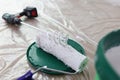 Paint mixer, roller brush and bucket with white paint on covered floor. Royalty Free Stock Photo