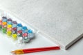 A paint-by-numbers kit, featuring a pre-drawn canvas with numbered sections, a set of colorful paint pots labeled with