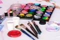 Paint palettes and brushes being used on an artist workshop table.