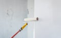 Paint roller applying paint on white wall.
