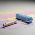 A paint roller with a blue, textured surface rests on a smooth, multi-colored paint Royalty Free Stock Photo