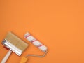 A paint roller and a large brush on an orange background