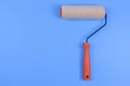 Paint roller with orange handle on blue background represents efficient surface coverage, commonly used in home improvement and Royalty Free Stock Photo