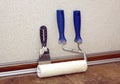 Paint rollesr and trowel stands in a room at baseboard near wall Royalty Free Stock Photo