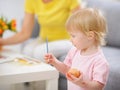 Paint smeared baby coloring Easter egg