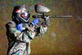 Paintball player in protective uniform shooting target with gun
