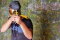 Paintball player in t-shirt shooting target with gun
