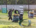 Paintball players in camouflage uniform and protective mask with gun on the field, shoot into enemies in the summer. Active sport Royalty Free Stock Photo