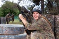 Paintball players of one team in camouflages and masks aiming with gun in shootout playing