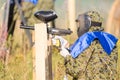 Paintball sport player in protective uniform and mask playing and shooting with gun outdoors. Royalty Free Stock Photo