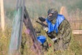 Paintball sport players in protective uniform and mask playing and shooting with gun outdoors. Royalty Free Stock Photo