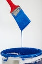 Paintbrush dripping blue paint. Closeup of a paintbrush dripping blue paint into a bucket. Royalty Free Stock Photo