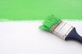 Paintbrush with green paint, painting over white board Royalty Free Stock Photo