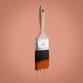 Paintbrush loaded with brown color dripping off the bristles,