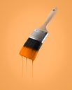 Paintbrush loaded with orange color dripping off the bristles. Royalty Free Stock Photo