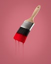 Paintbrush loaded with red color dripping off the bristles.