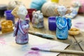 Paintbrush, paint in jars and handmade figurines `Angels of tender emotion` from clay pottery on wooden table.