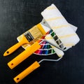 Paintbrush, paint rollers and colorful paint samples on dark background Royalty Free Stock Photo