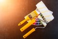 Paintbrush, paint rollers and colorful paint samples on dark background in rays of the sun, top view Royalty Free Stock Photo