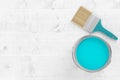 Paintbrush with silver paint bucket with cyan paint on white wooden floor background, home renovation concept flat lay top view