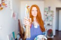 Paintbrushes holded by young redhead woman painter in artist workshop
