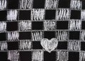 Painted chess board and white white heart on a black board