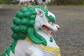 A painted concrete Buddhist Shishi dragon statue with a blurred background