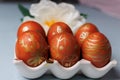 Painted Easter eggs are arranged on a decorative tray with a flower on a gray background. Close-up. Royalty Free Stock Photo