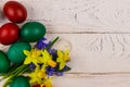 Painted Easter eggs and bouquet of yellow daffodils and blue scilla flowers on white wooden background. Easter composition Royalty Free Stock Photo