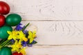 Painted Easter eggs and bouquet of yellow daffodils and blue scilla flowers on white wooden background. Easter composition Royalty Free Stock Photo
