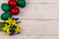 Painted Easter eggs and bouquet of yellow daffodils and blue scilla flowers on white wooden background Royalty Free Stock Photo